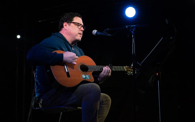 Image of musician performing on stage with guitar