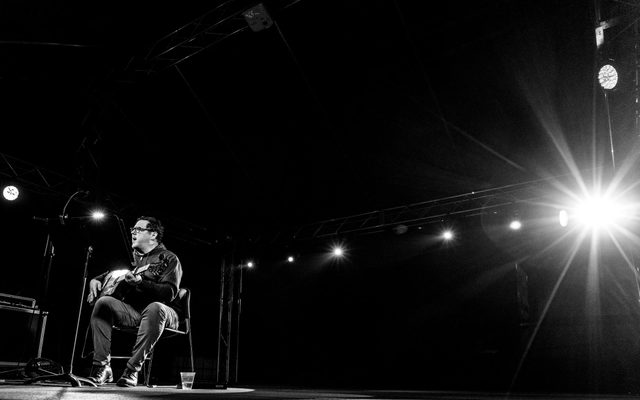 Black and white image of musician performing on stage with guitar