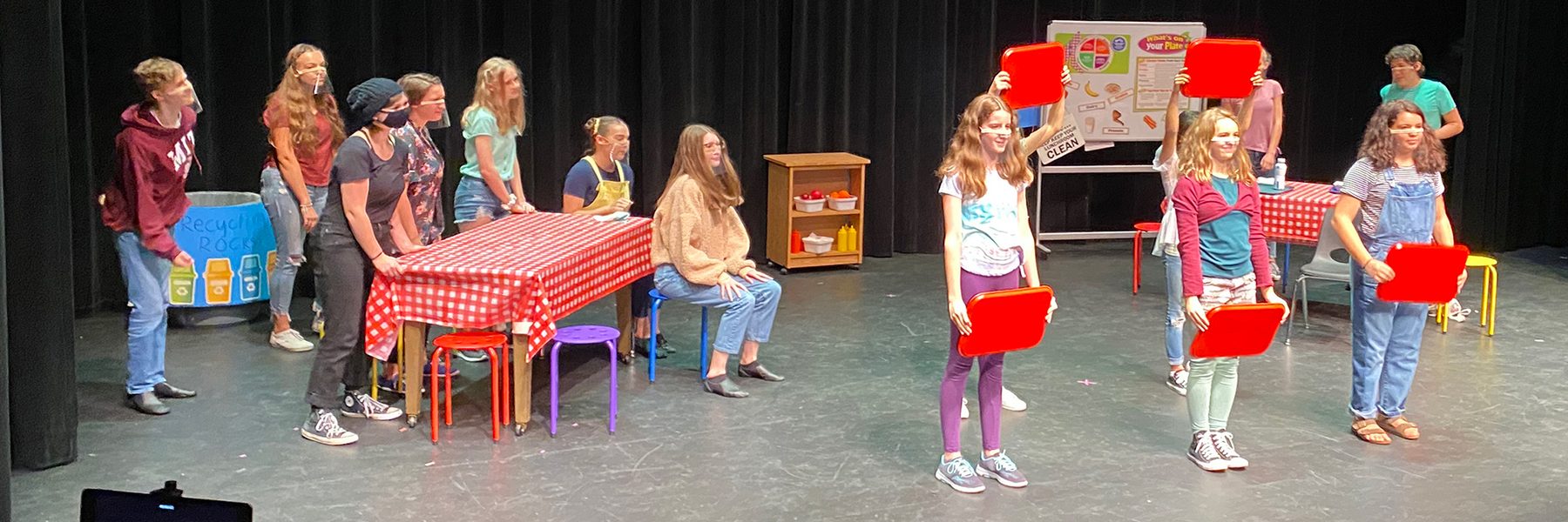 Teenagers on stage in what looks like a cafeteria scene