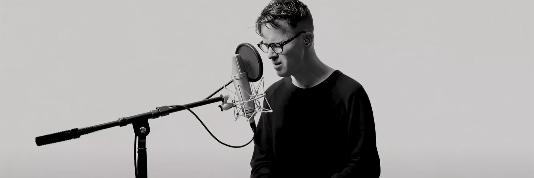 Black and white image of Ryan Lott playing the keyboard and singing into a microphone
