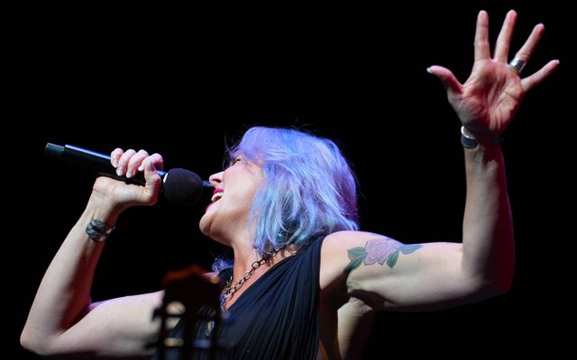 Photo of woman with brightly colored hair singing into a microphone