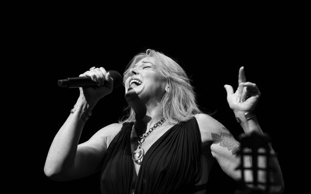 Black and white Photo of woman with brightly colored hair singing into a microphone