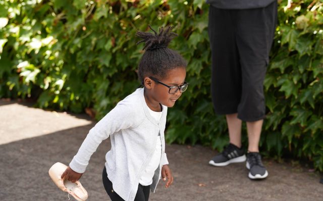 A young girl holding a ballet slipper