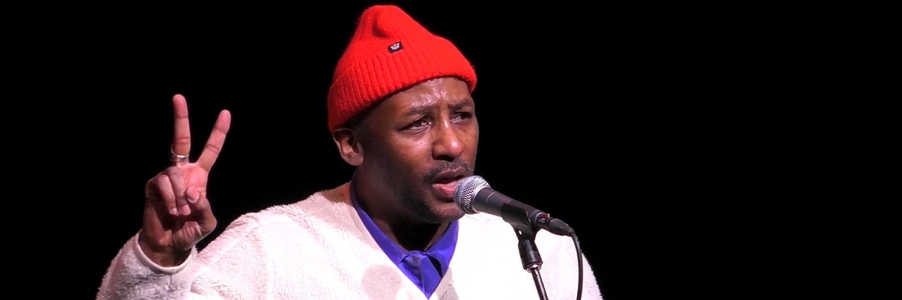 Picture of Redray Frazier holding up two fingers in front of microphone